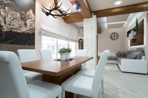 a dining room with a wooden table and white chairs at Apartamenty Comfort & Spa Stara Polana in Zakopane