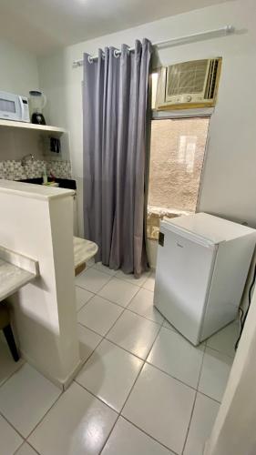 a kitchen with a small refrigerator and a window at Studio Bia in Natal