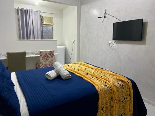 a bedroom with a bed with a blue blanket and a tv at Studio Bia in Natal