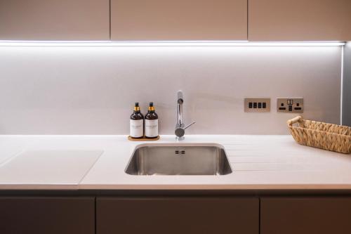 two bottles of beer sitting on top of a kitchen sink at Modern Apartment in Central Manchester in Manchester