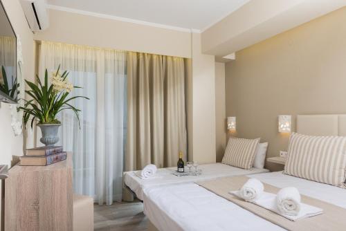 a hotel room with two beds and a couch at Ammos Beach Seaside Luxury Suites Hotel in Olympic Beach