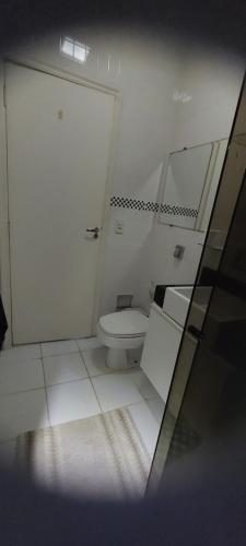 a white bathroom with a toilet and a mirror at Suíte na Cobertura Enseada in Guarujá
