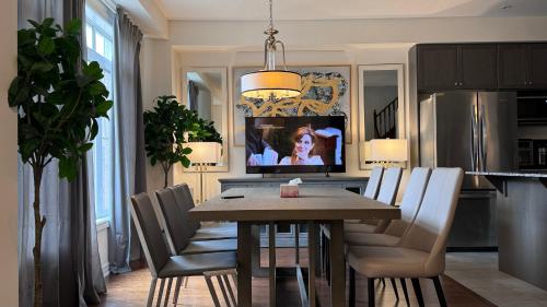 a dining room with a table and chairs and a television at 9 Queen Beds, 18 Guests-Kleinburg Luxe Crown Town Residence in Vaughan
