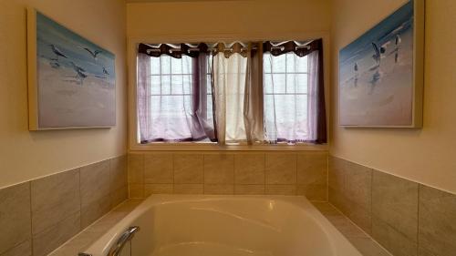 a bath tub in a bathroom with two windows at 9 Queen Beds, 18 Guests-Kleinburg Luxe Crown Town Residence in Vaughan