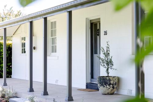 a white house with a potted plant on the porch at Wisteria Cottage Rylstone in Rylstone