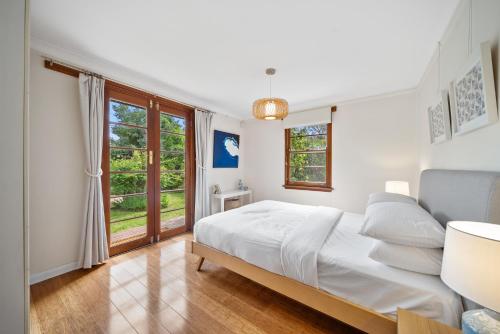 a white bedroom with a bed and a window at Comfortable 3-Bed Haven Near Canberra Attractions in Narrabundah