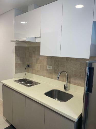 a kitchen with a sink and white cabinets at ARC Studio Unit at 38th Park in Cebu City