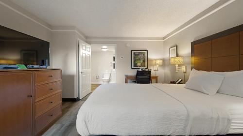 a bedroom with a large white bed and a dresser at Howard Johnson by Wyndham Sacramento Downtown in Sacramento