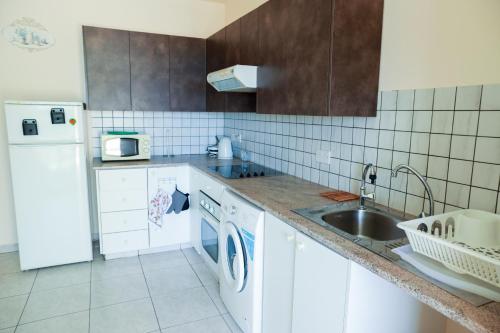a white kitchen with a sink and a dishwasher at Mackenzie Apartment 101 in Larnaka