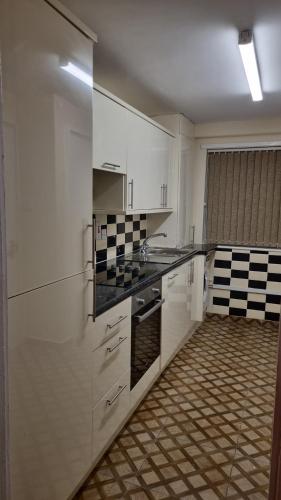 a kitchen with white cabinets and black and white tiles at Apple valley in Manchester