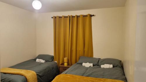 a bedroom with two beds and a yellow curtain at Apple valley in Manchester