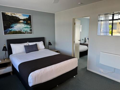 a bedroom with a large bed and a bathroom at Academy Motor Inn in Tauranga