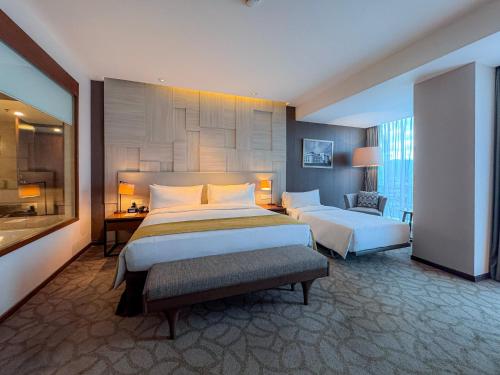 a large hotel room with two beds and a chair at Crowne Plaza Bandung by IHG in Bandung
