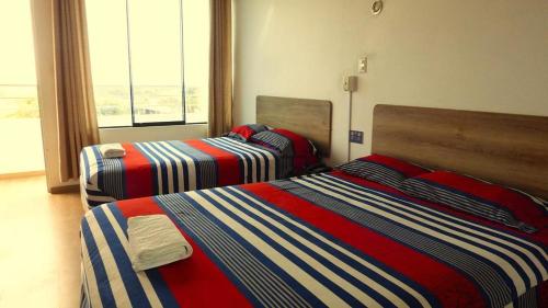 two beds in a room with a window at Camber Inn in Máncora
