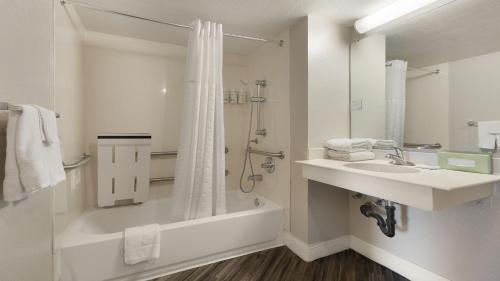 a bathroom with a tub and a sink and a shower at Howard Johnson by Wyndham Sacramento Downtown in Sacramento