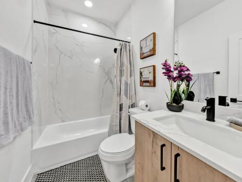a white bathroom with a tub and a toilet and a sink at Sophisticated Dallas Retreat l Prime Location! in Dallas