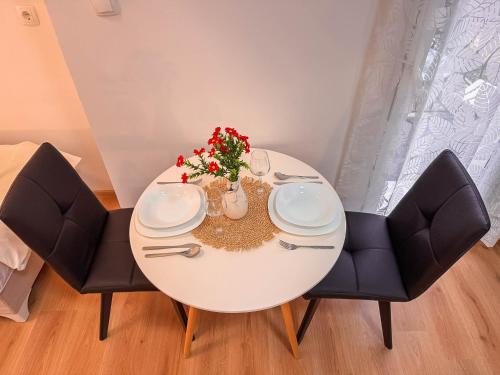 a white dining room table with two chairs and flowers at Apartments Seyda in Sarajevo