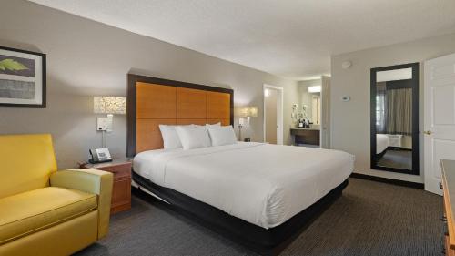 a hotel room with a large bed and a yellow chair at Howard Johnson by Wyndham Sacramento Downtown in Sacramento