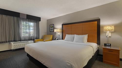 a hotel room with a large bed and a chair at Howard Johnson by Wyndham Sacramento Downtown in Sacramento