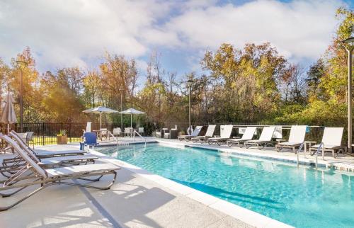 a swimming pool with chaises and chairs in a resort at Holiday Inn Express Chattanooga - Hamilton Place in Chattanooga