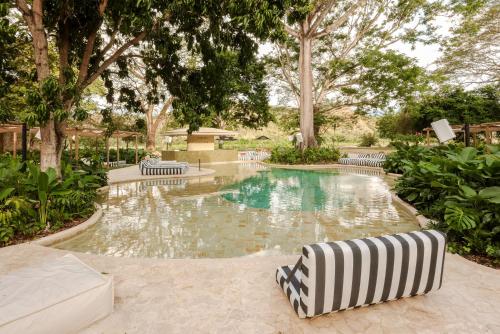 a swimming pool with a striped chair in a yard at Arde La Selva in Santa Fe de Antioquia