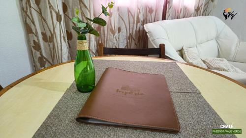 a table with a book and a green bottle on it at Pousada Fazenda Vale Verde in Sete Barras