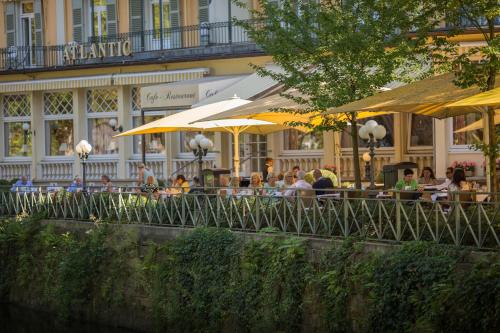 a group of people sitting at a restaurant with umbrellas at Atlantic Parkhotel in Baden-Baden