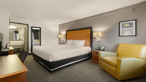 a hotel room with a bed and a chair at Howard Johnson by Wyndham Sacramento Downtown in Sacramento