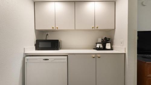 a small kitchen with white cabinets and a microwave at Howard Johnson by Wyndham Sacramento Downtown in Sacramento