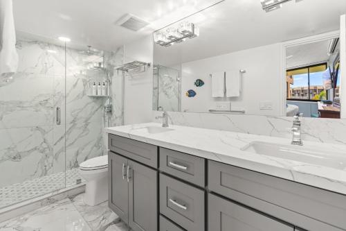 a white bathroom with a sink and a shower at Rear Ocean View 2 Bedroom Single Level Condo at Kamaole Sands 9-305 in Wailea