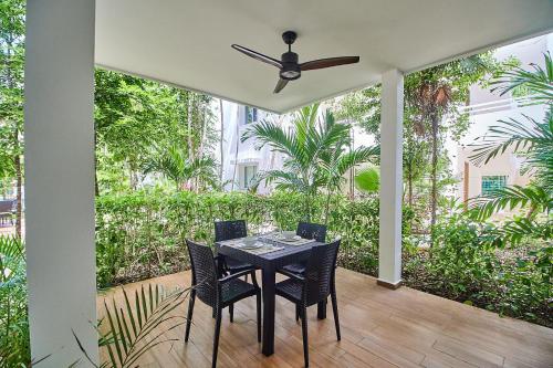 a table and chairs on a porch with a ceiling fan at Aldea Zama Condo with 2 Pools, Gym, Yoga Deck and BBQ Grill in Tulum