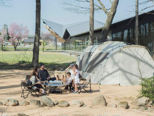 a group of people sitting around a table next to a tent at Snow Peak LAND STATION HAKUBA in Hakuba
