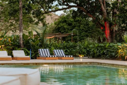 two lounge chairs sitting next to a swimming pool at Arde La Selva in Santa Fe de Antioquia
