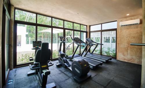 Un gimnasio con varias máquinas de correr en una habitación con ventanas. en Aldea Zama Condo with 2 Pools, Gym, Yoga Deck and BBQ Grill, en Tulum