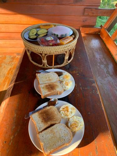 two plates of sandwiches and a basket of bread at บ้านพักเคียงนา in Ban Sop Mae Klang