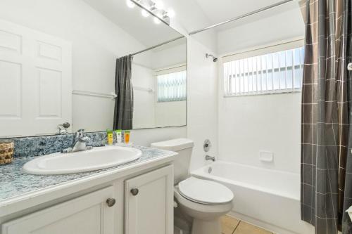 a white bathroom with a sink and a toilet at Luxury 4-Bedroom Home with Private Pool, Jacuzzi, AC, Wi-Fi, Cable TV, 5 Minutes from Disney in Kissimmee