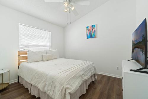 a white bedroom with a bed and a window at Luxury 4-Bedroom Home with Private Pool, Jacuzzi, AC, Wi-Fi, Cable TV, 5 Minutes from Disney in Kissimmee