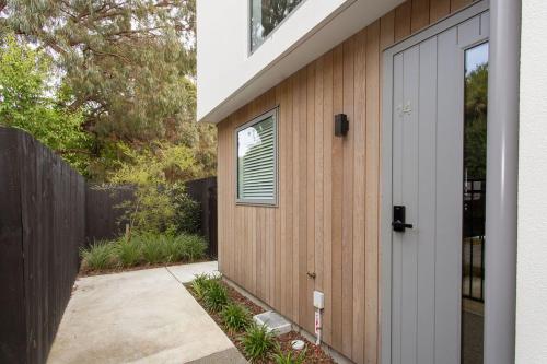 a wooden building with a door next to a sidewalk at Immaculate Presentation, Carpark in Christchurch