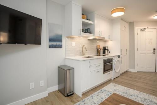 a white kitchen with a sink and a microwave at KING Bed STUDIO in the Village in Whistler