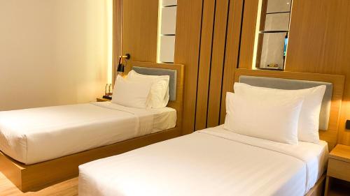 two beds in a hotel room with white pillows at Eagle Hotel Wonosobo, Azana Hotels Collection in Kalianget