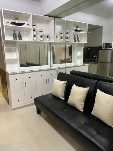 a living room with a black couch and white cabinets at Sea Residences MoA Manila in Manila