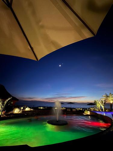 a fountain in the middle of a pool at night at Lu Vee Oasis in Puerto Escondido