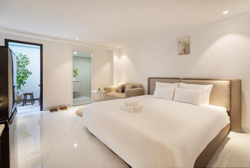 a white bedroom with a large bed and a living room at The Royal Sky - Phu My Hung in Ho Chi Minh City