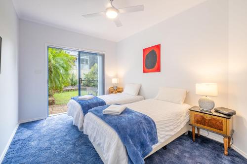 two beds in a room with a window at Tah Villa 1, 68 Marine Dr - stunning views, linen and air con in Fingal Bay