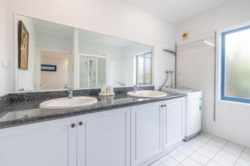 a bathroom with two sinks and a large mirror at Tah Villa 1, 68 Marine Dr - stunning views, linen and air con in Fingal Bay