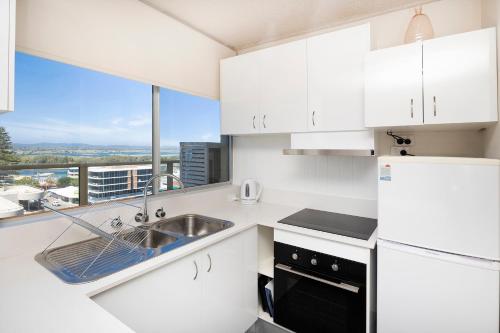 a kitchen with white cabinets and a sink and a window at Ebbtide 40 in Forster