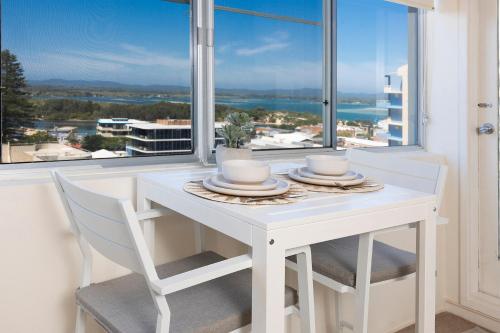 a white table and chairs with a view of the ocean at Ebbtide 40 in Forster