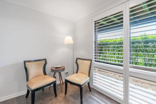 two chairs and a table in a room with a window at Kiama Mountain Views Studio in Kiama