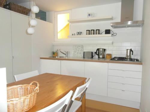 a kitchen with white cabinets and a wooden table at River View Penthouse in Lisbon