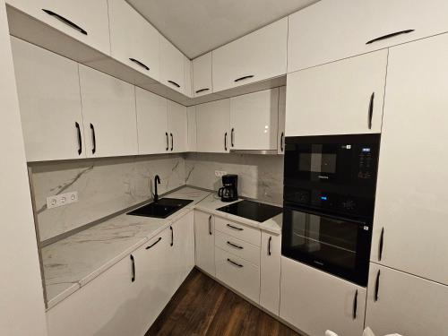 a white kitchen with white cabinets and black appliances at Concept Luxury in Mediaş